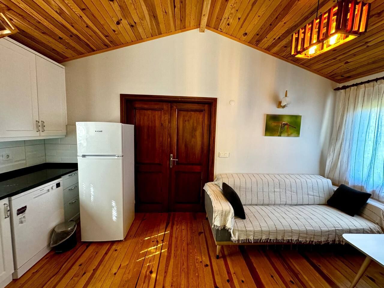 A compact kitchen with a white refrigerator, wooden cabinets, and a wooden ceiling.