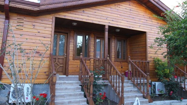 A wooden cabin with a porch, wooden steps, and a small garden area with flowers. - Elly's Home (Datça)