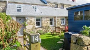 A stone house with a number 14 sign, a stone wall, and a small garden with a lawn and a barbecue area. - 14 Boscaswell Downs (Penzance)