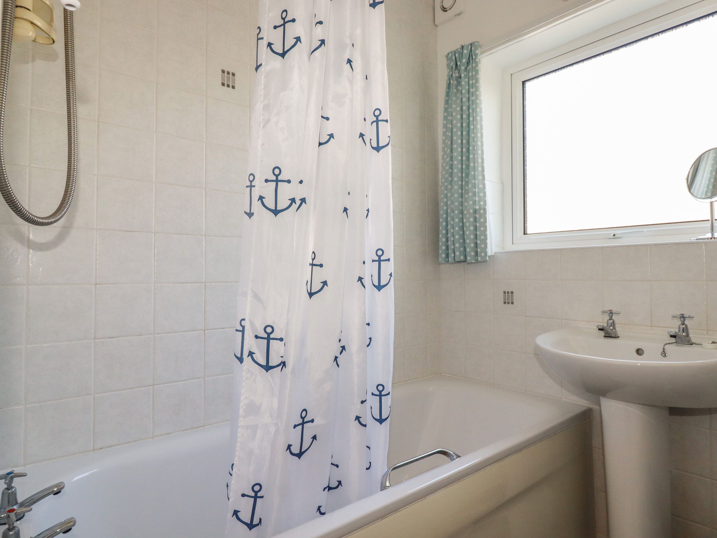 Un bagno con vasca, doccia, lavandino e finestra con tende.