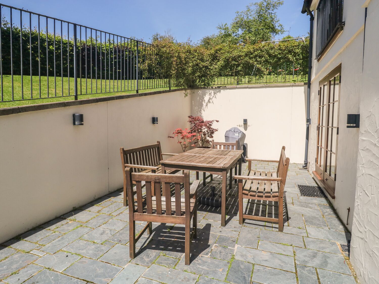 A patio with a table and chairs, a grill, and a potted plant.