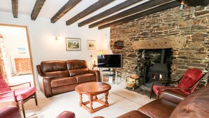 Una sala de estar acogedora con chimenea de piedra, muebles de cuero y un televisor.