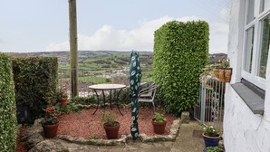 Une terrasse avec une table et des chaises, entourée de plantes en pot et offrant une vue sur la campagne.