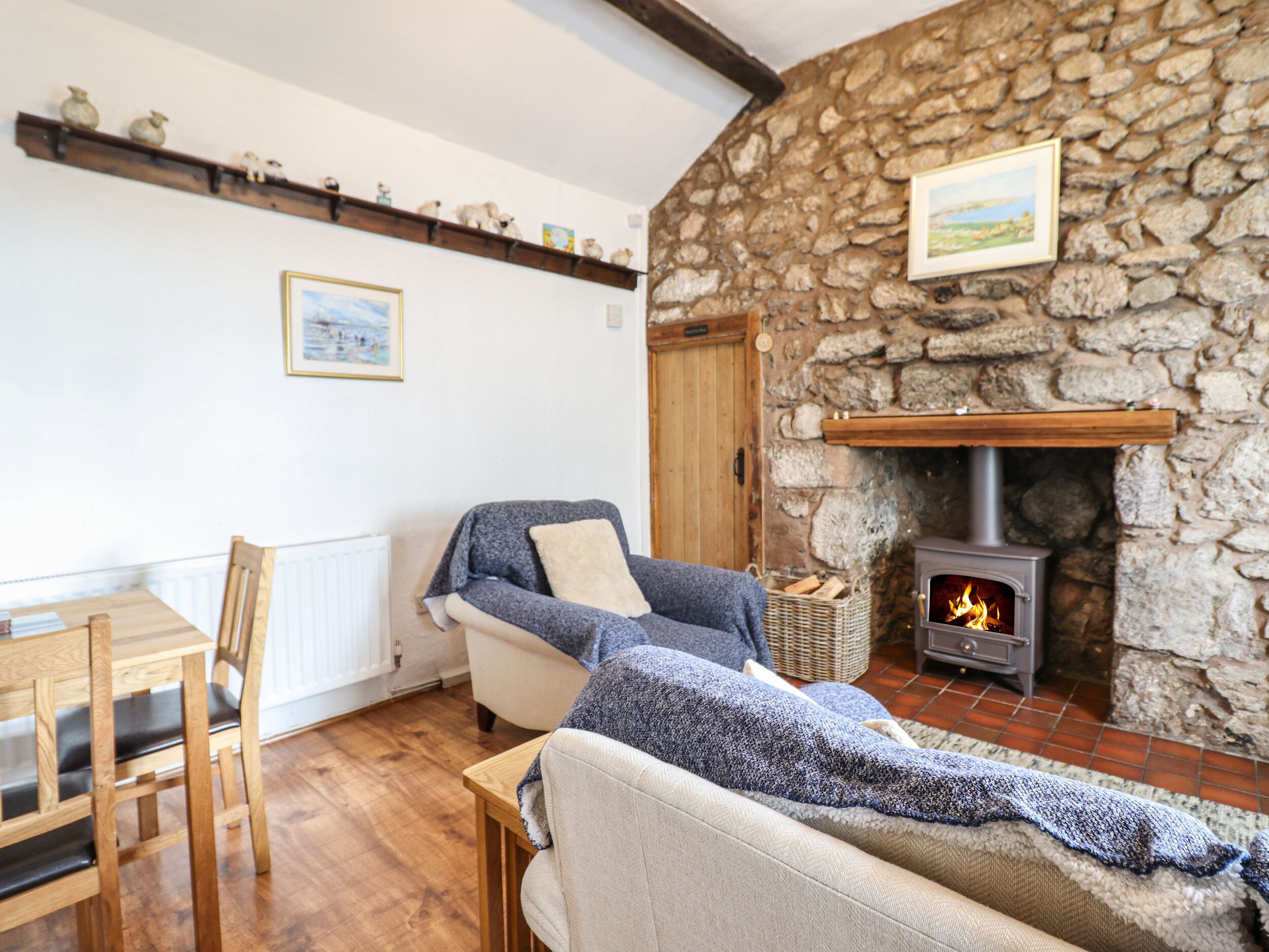 A cozy living room with a stone wall, a fireplace, a sofa, a wooden table, and a chair.