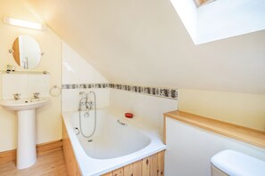 A modern bathroom with a freestanding bathtub, a pedestal sink, and a wooden vanity. - Dunstaffnage Cottage (Grantown-on-Spey)