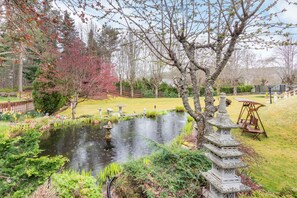 A serene garden with a pond, stone lanterns, and a wooden swing. - Dunstaffnage Cottage (Grantown-on-Spey)