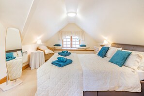 A bedroom with two beds, a window, a mirror, and a bedside table with a lamp. - Dunstaffnage Cottage (Grantown-on-Spey)