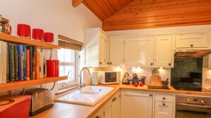 Una cocina moderna con armarios blancos, encimera de madera, un fregadero, un tostador, un hervidor y una estufa.