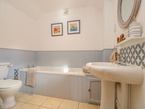 A bathroom with a bathtub, a toilet, and a sink. There are two framed pictures on the wall. - Pond Cottage (Truro)