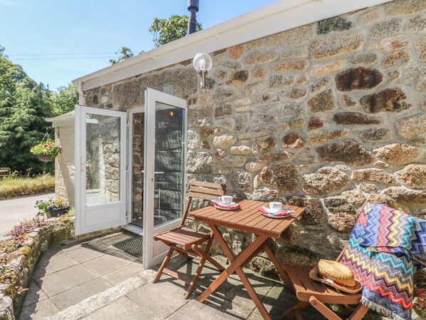 A stone building with a glass door leading to a patio with a wooden table and chairs.