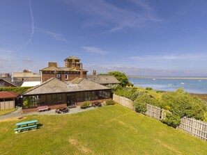 A coastal property with a large house, a conservatory, and a grassy lawn. - Roa Island House (Barrow-in-Furness)