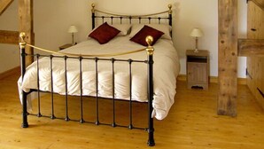 A bed with a metal frame and wooden headboard in a room with wooden beams and a wooden floor.