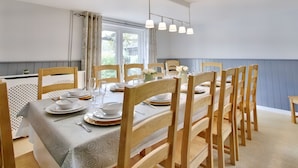 A dining area with a table set for four, surrounded by wooden chairs, with a window providing natural light.