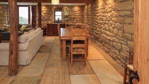 A rustic interior with stone walls, wooden furniture, and a stone fireplace. - Usherwoods Barn (Lancaster)