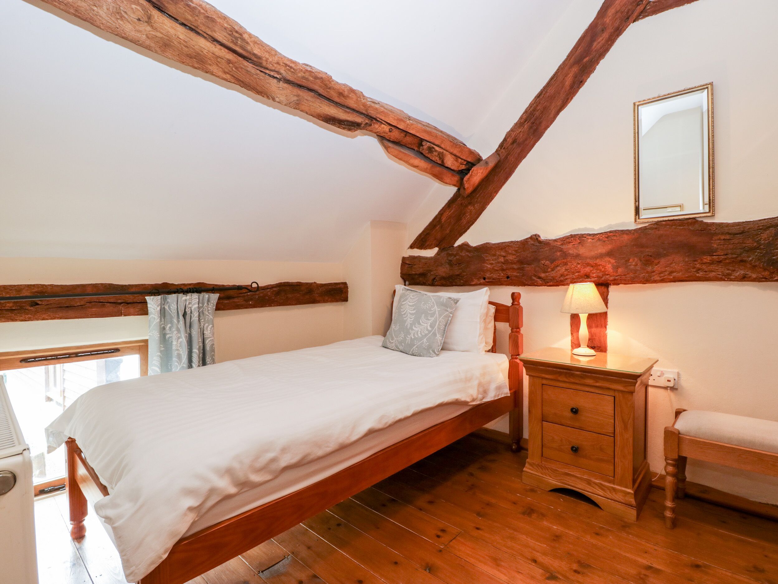 Una camera da letto con un letto in legno, un comodino con una lampada e una finestra con tende.