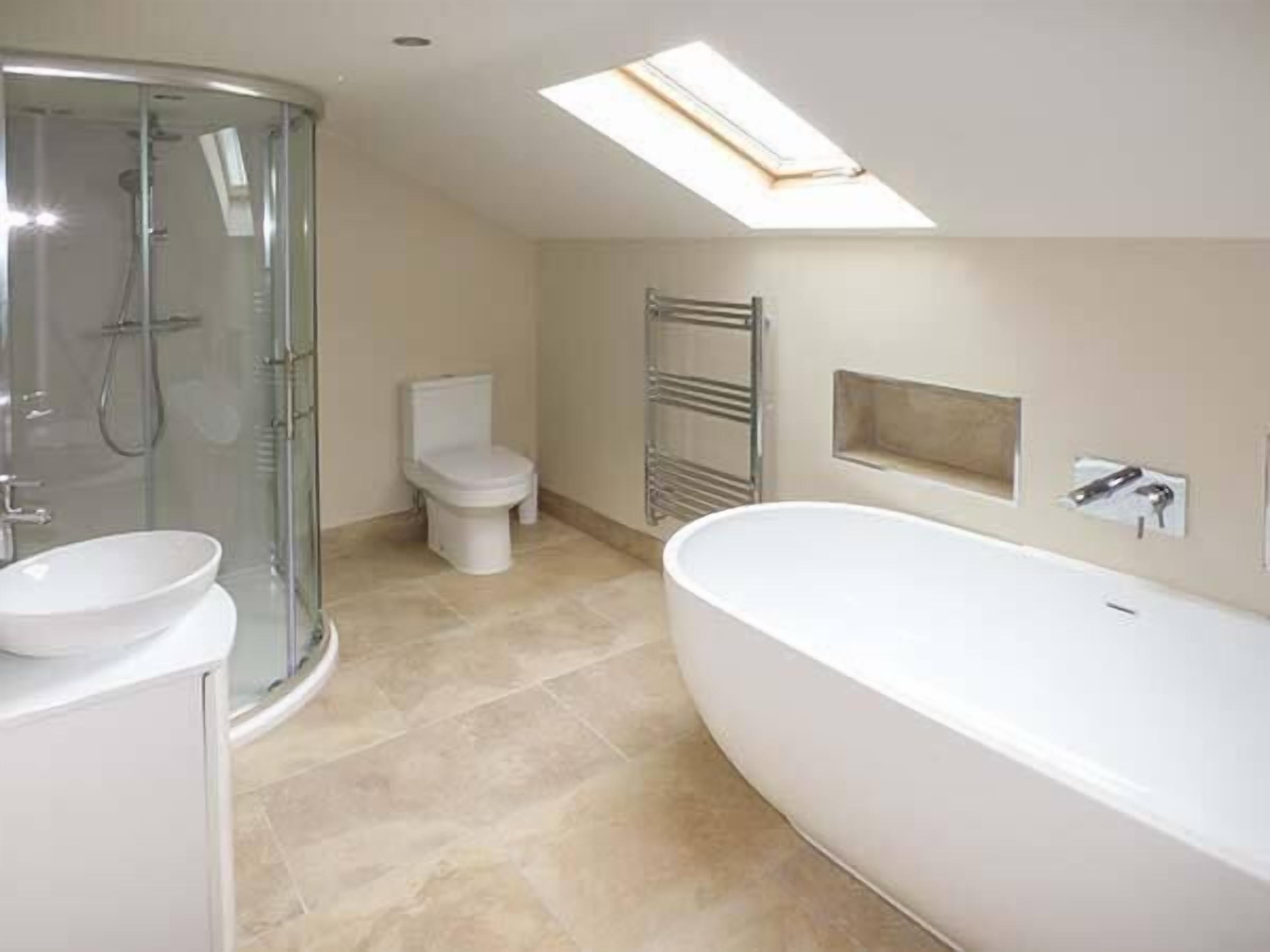 A modern bathroom with a glass-enclosed shower, a freestanding bathtub, and a toilet.