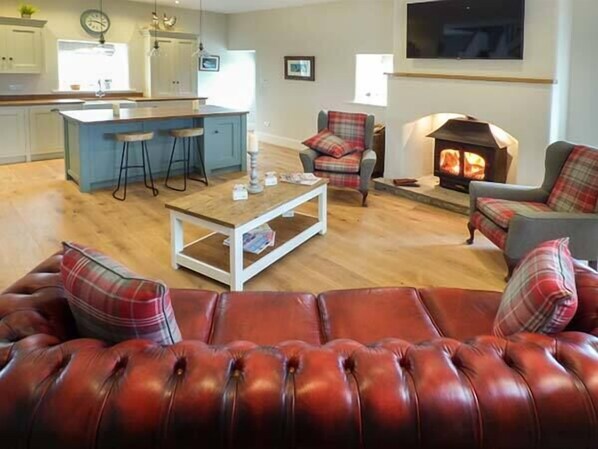 A living room with a leather sofa, a coffee table, and a fireplace. - Ox Hey Barn (Clitheroe)