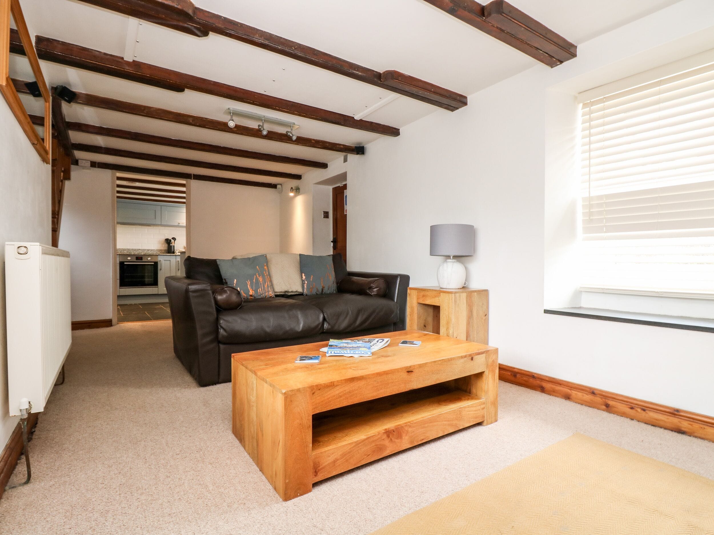 Una sala de estar con una mesa de centro de madera, un sofá de cuero y una lámpara en una mesita auxiliar.