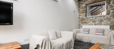 A cozy living room with a stone wall, a flat-screen TV, and a wooden coffee table.