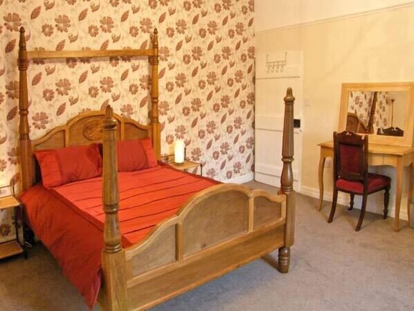 A four-poster bed with a wooden headboard, a desk with a chair, and a mirror. - Hendre Aled Farmhouse (Denbigh)