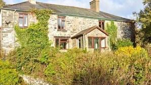 A stone house with a green roof, multiple windows, and a chimney. - Hendre Aled Farmhouse (Denbigh)