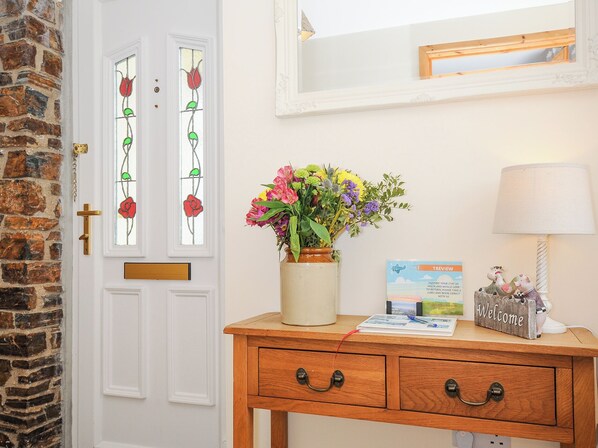 A wooden desk with a vase of flowers, a lamp, and a welcome sign. - Treview (Launceston)