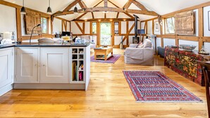 Um loft espaçoso com vigas de madeira aparente, uma grande ilha na cozinha, um espaço de estar acolhedor e vista para o exterior.