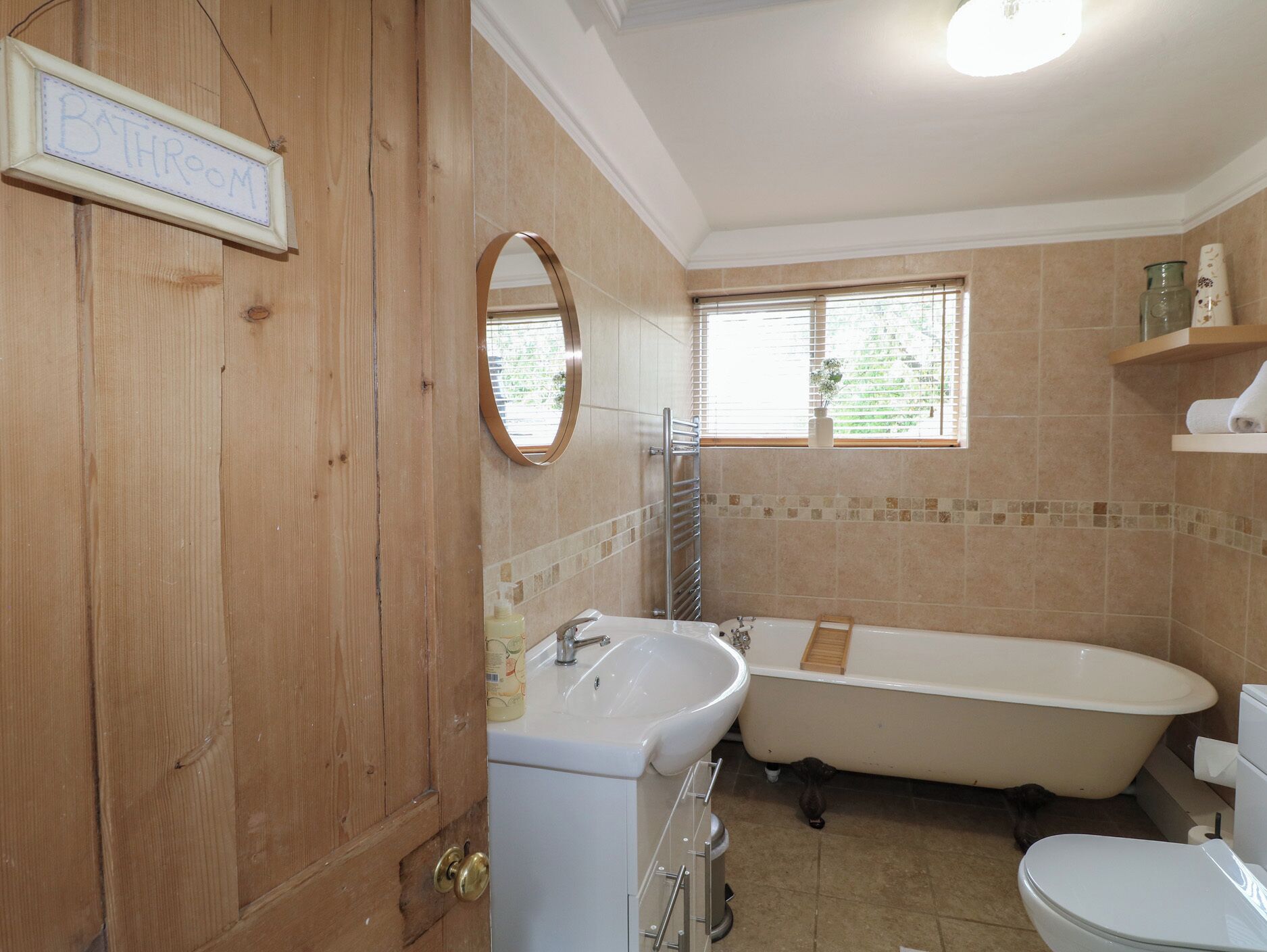 A bathroom with a wooden door, a sink, a bathtub, and a toilet.