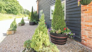 A building with a gravel driveway, potted plants, and a hanging flower basket. - The Wain House (Craven Arms)