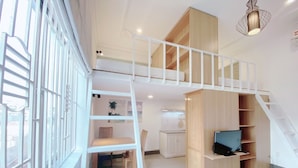 A spacious room with a loft area, a staircase, a dining table, and a TV. - Halo Serviced Apartment (Ho Chi Minh City)