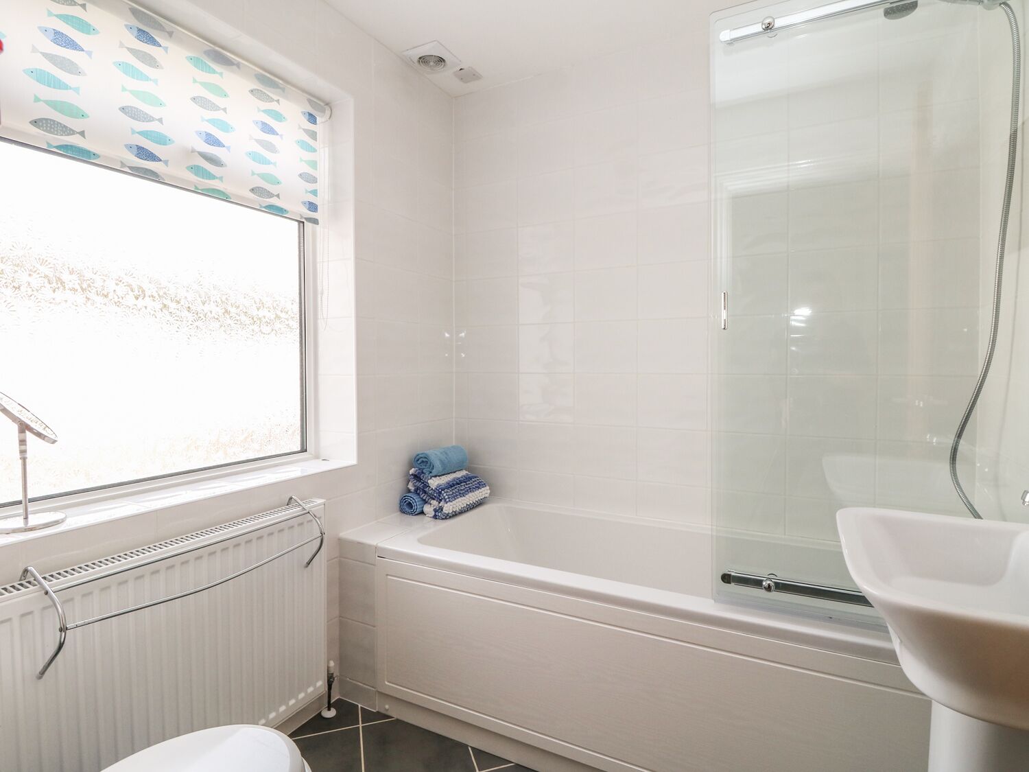 A bathroom with a bathtub, a toilet, and a window with a view of the outside.