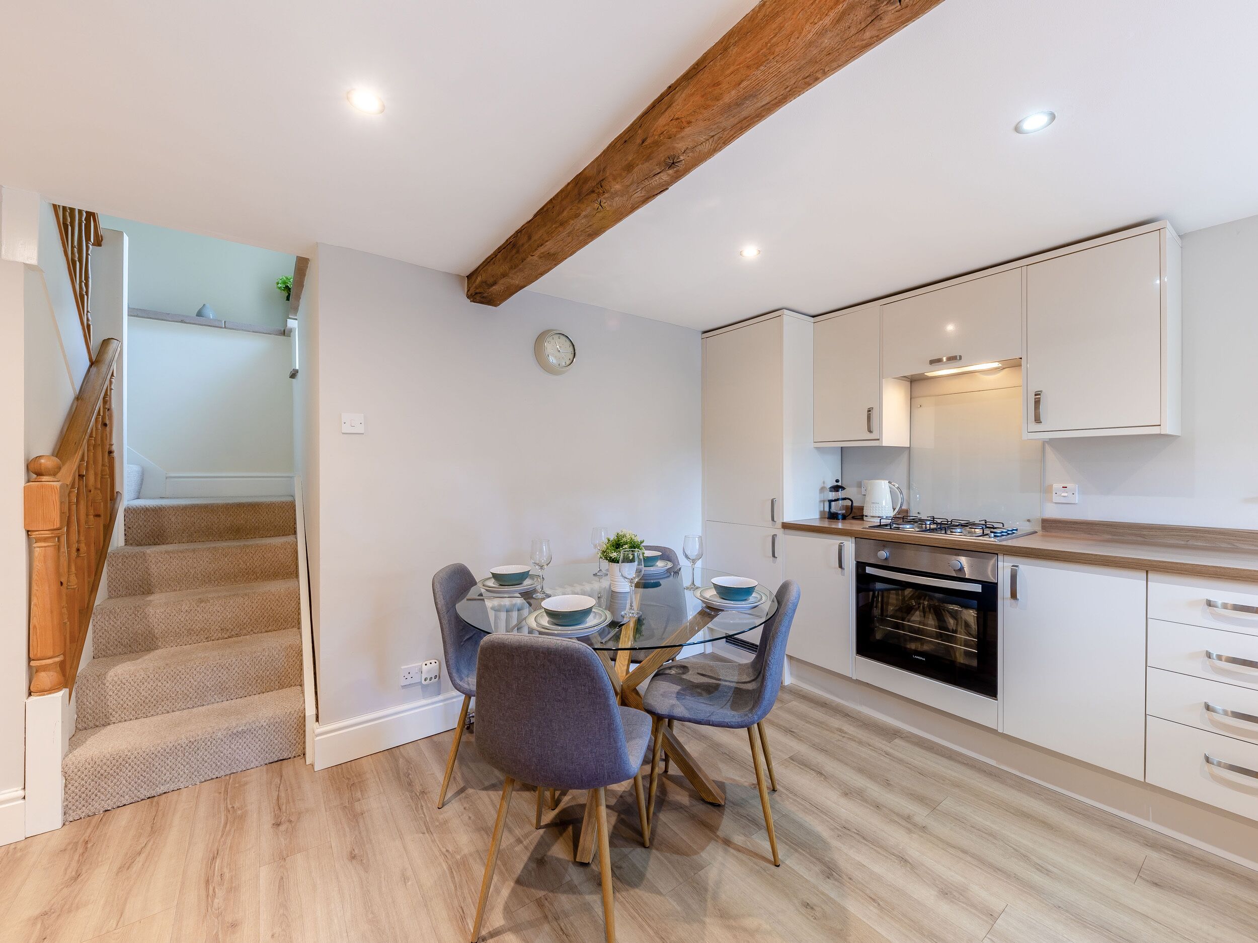 A modern kitchen with white cabinets, a wooden ceiling, and a dining area with a table set for four.
