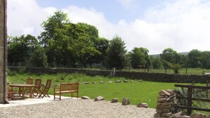 A patio area with outdoor seating and a stone wall. - Goldcrest (Leek)