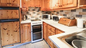 Una cocina con armarios de madera, estufa, microondas, tostadora y fregadero.