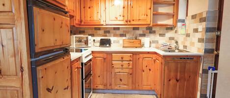 A kitchen with wooden cabinets, a stove, a microwave, and a toaster.