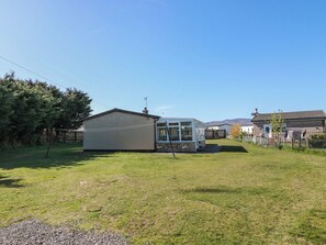 A residential area with a small house, a conservatory, and a fenced yard.