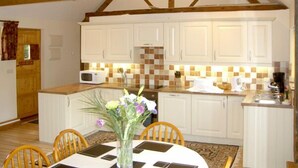 A kitchen with white cabinets, a microwave, and a tiled backsplash. - Happy Union Stables (Llandrindod Wells)