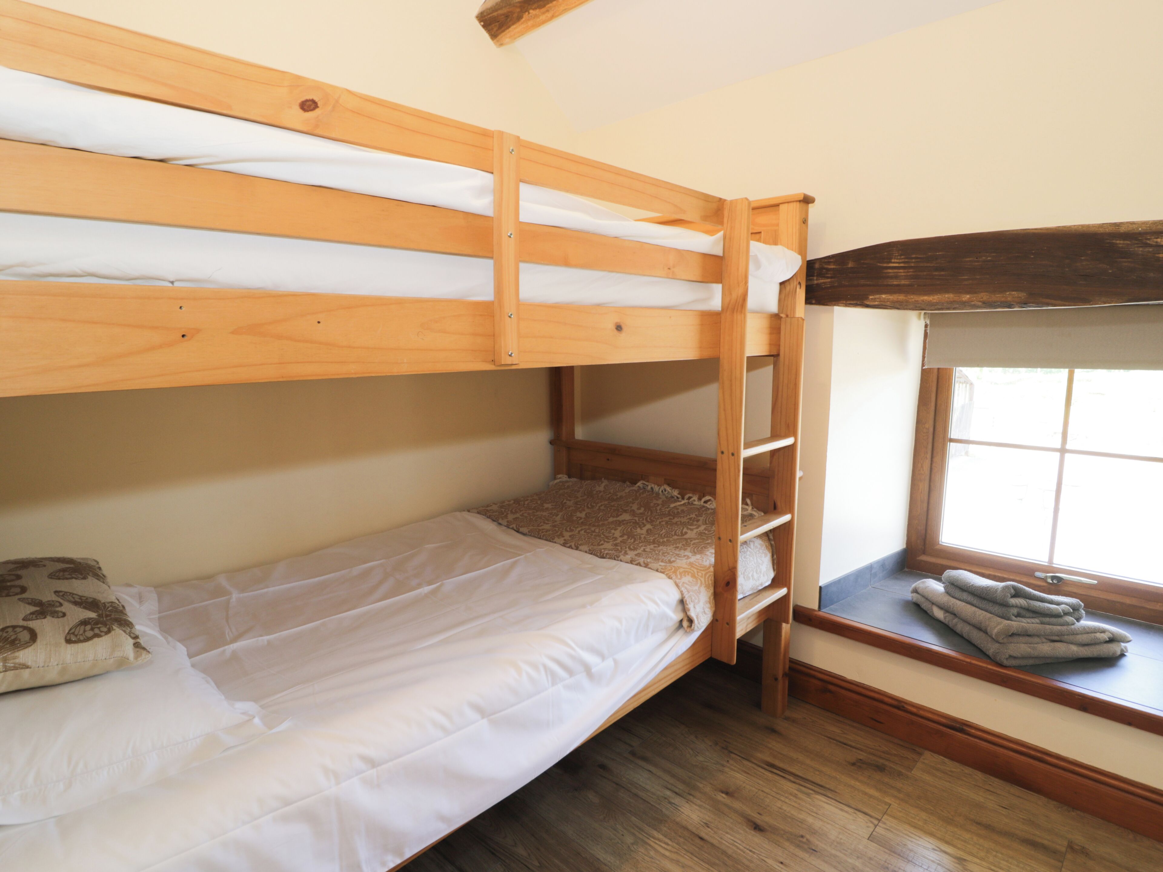 Ein Stockbett mit einer Leiter, ein Fenster mit Blick und eine kleine Sitzecke mit einer Decke.