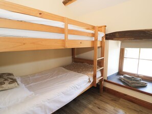 A bunk bed with a ladder, a window with a view, and a small seating area with a blanket. - Cornel Clyd (Abergele)