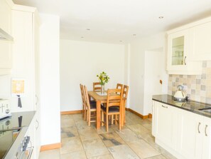 A compact kitchen with a dining table, chairs, a kettle, and a stove. - Ghyll Bank Byre (Kendal)