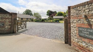A gravel driveway leading to a gated entrance with a sign reading "Hedge End Farm Cottages". - Corner Barn (Blandford Forum)