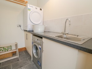 A compact kitchen with a washing machine, a sink, and a countertop. - Little Crake Howe (Kendal)