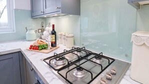 A modern kitchen with a gas stove, cabinets, and a window.