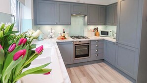 A modern kitchen with grey cabinets, a white countertop, a gas stove, and a microwave.