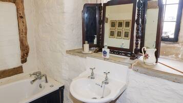 Un baño con un lavamanos blanco, una bañera y un espejo sobre el lavamanos.