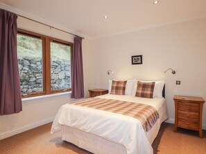 Relax in this serene bedroom with a large bed, two nightstands, and a wall-mounted lamp.
