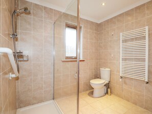 Enjoy a refreshing shower in the walk-in shower with a glass door, a standalone toilet, and a towel rack.