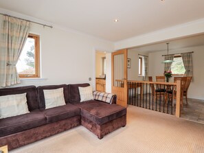 Relax in this spacious room with a large sofa, dining table, and mirror.
