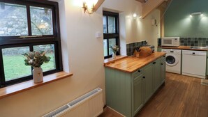 Una cocina con encimera de madera, lavadora, microondas y fregadero.