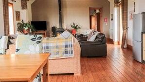 Een gezellige woonkamer met houten balken, een bank, een tafel en een televisie.